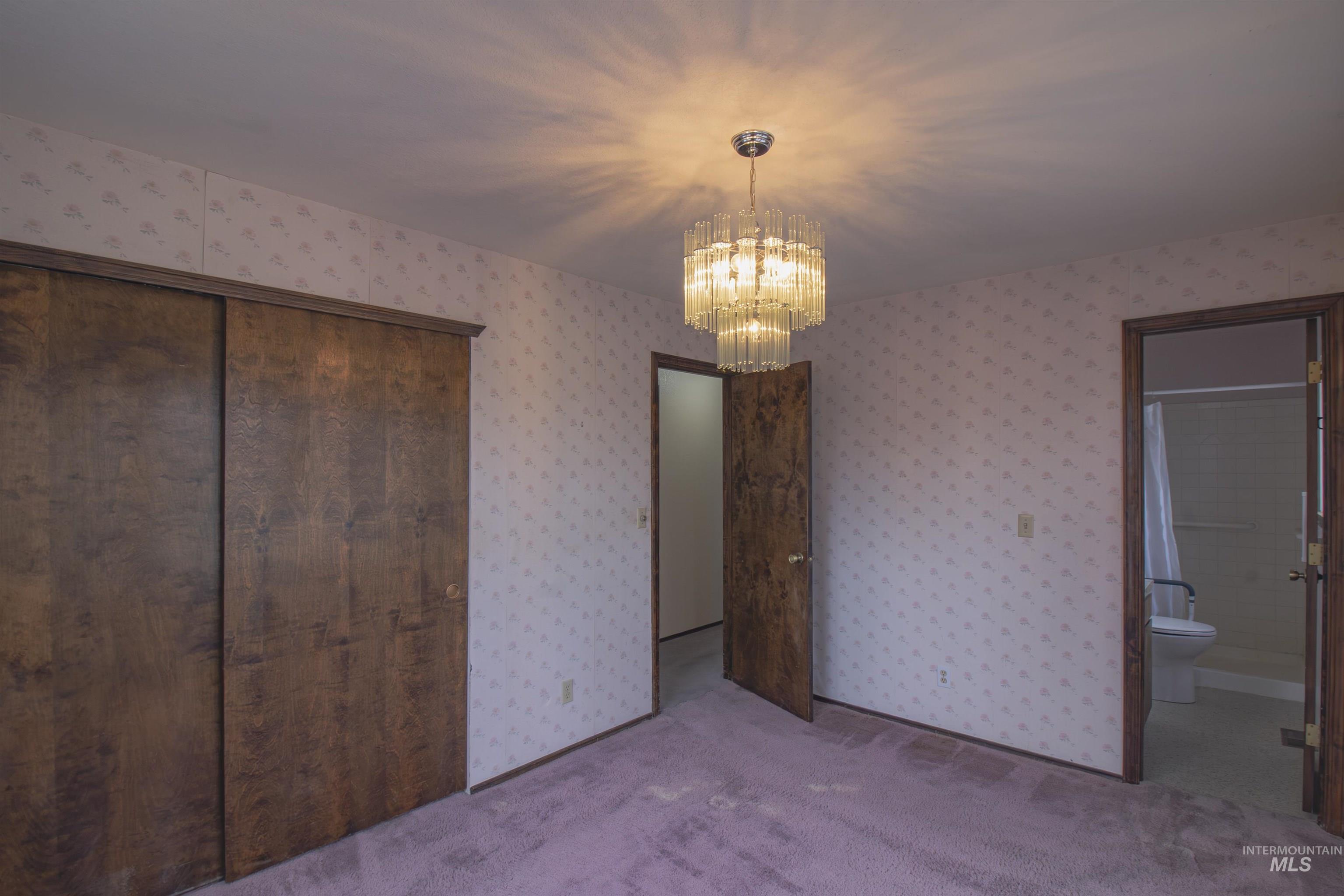 2465 Center Avenue Payette, ID 83661 - Photo 20 of 39 Bedroom featuring light carpet, a chandelier, a closet, wallpapered walls, and an ensuite bathroom