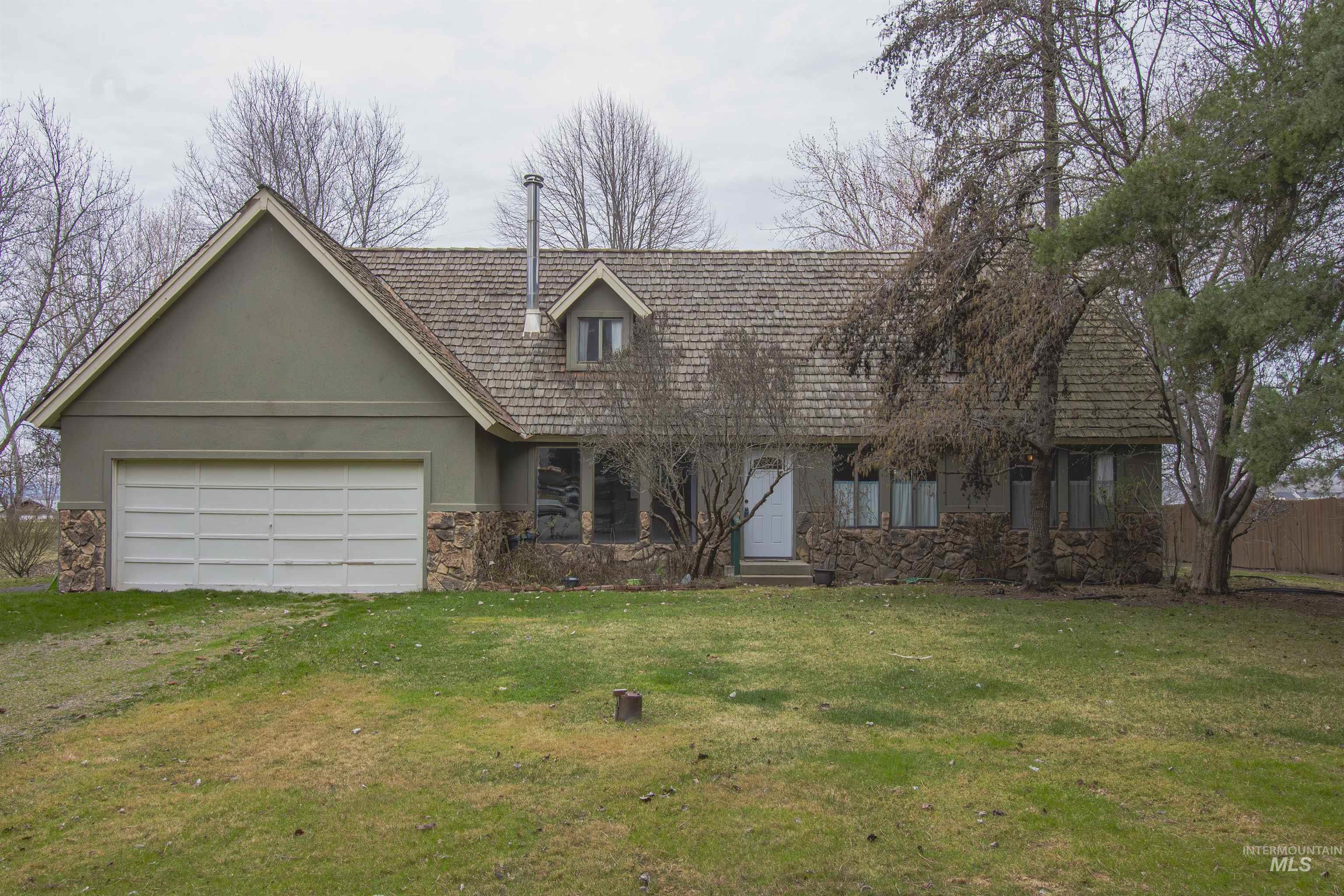 2465 Center Avenue Payette, ID 83661 - Photo 3 of 39 Front of home featuring stone siding, stucco siding, a front lawn, driveway, and a garage