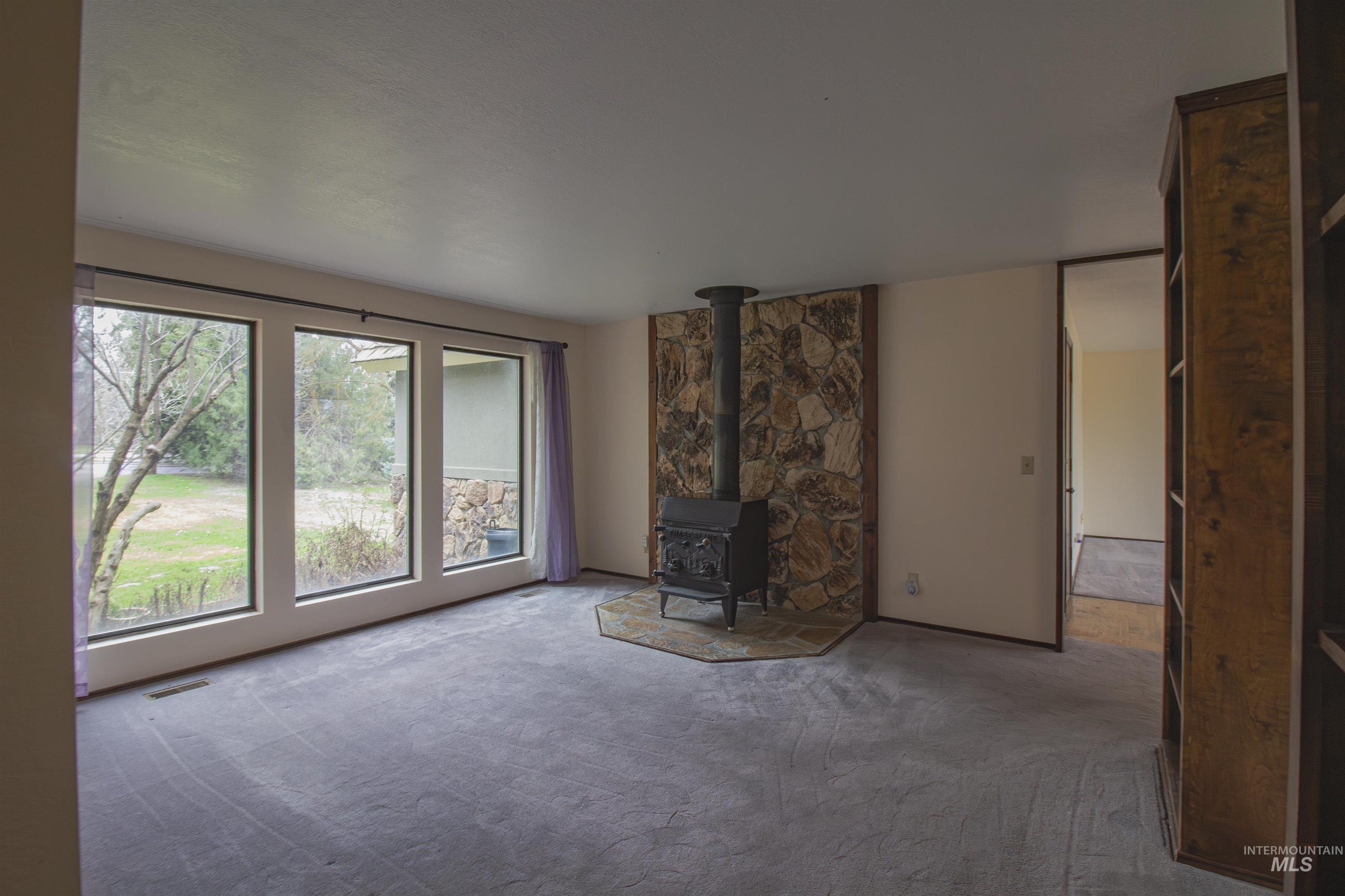 2465 Center Avenue Payette, ID 83661 - Photo 5 of 39 Unfurnished living room featuring a wood stove and carpet flooring