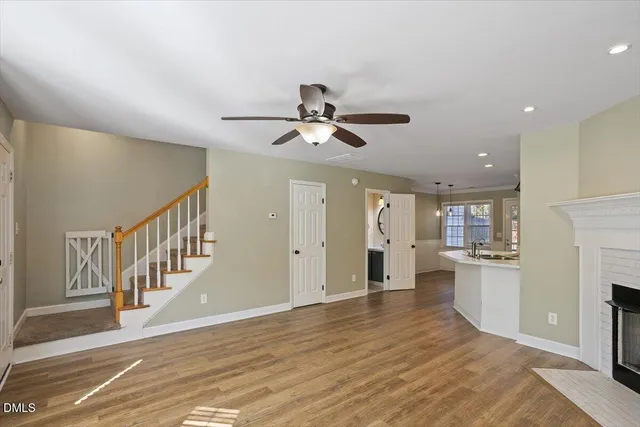 a view of an empty room and kitchen with wooden floor and a ceiling fan