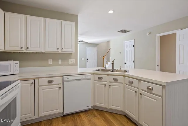 a kitchen with white cabinets and sink