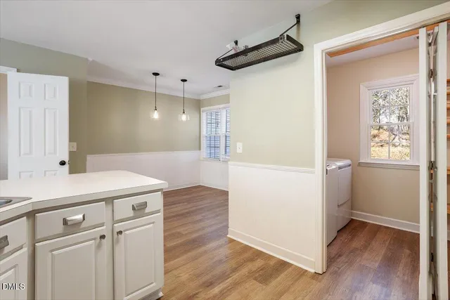 a view of a hallway to a room with wooden floor and cabinet