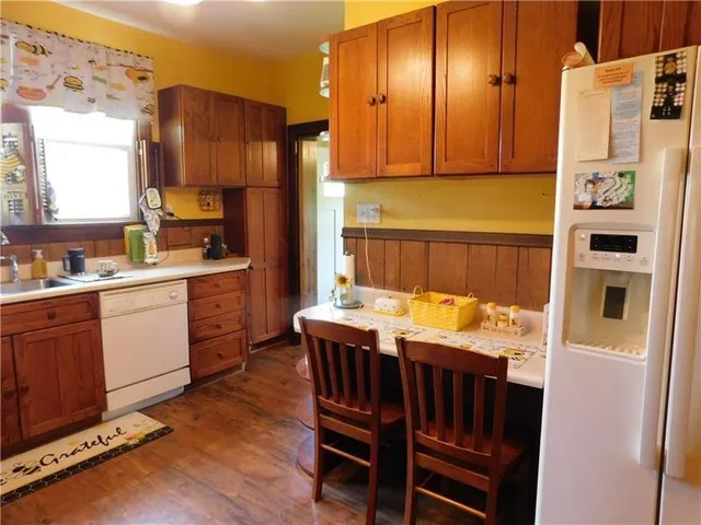 a kitchen with granite countertop a refrigerator a stove and wooden cabinets