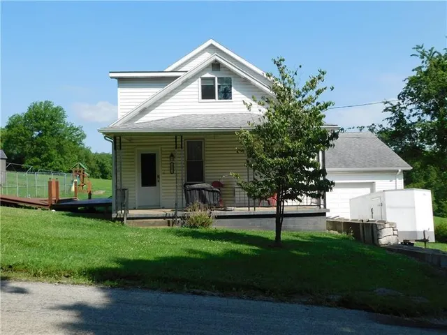 a front view of a house with a yard and trees