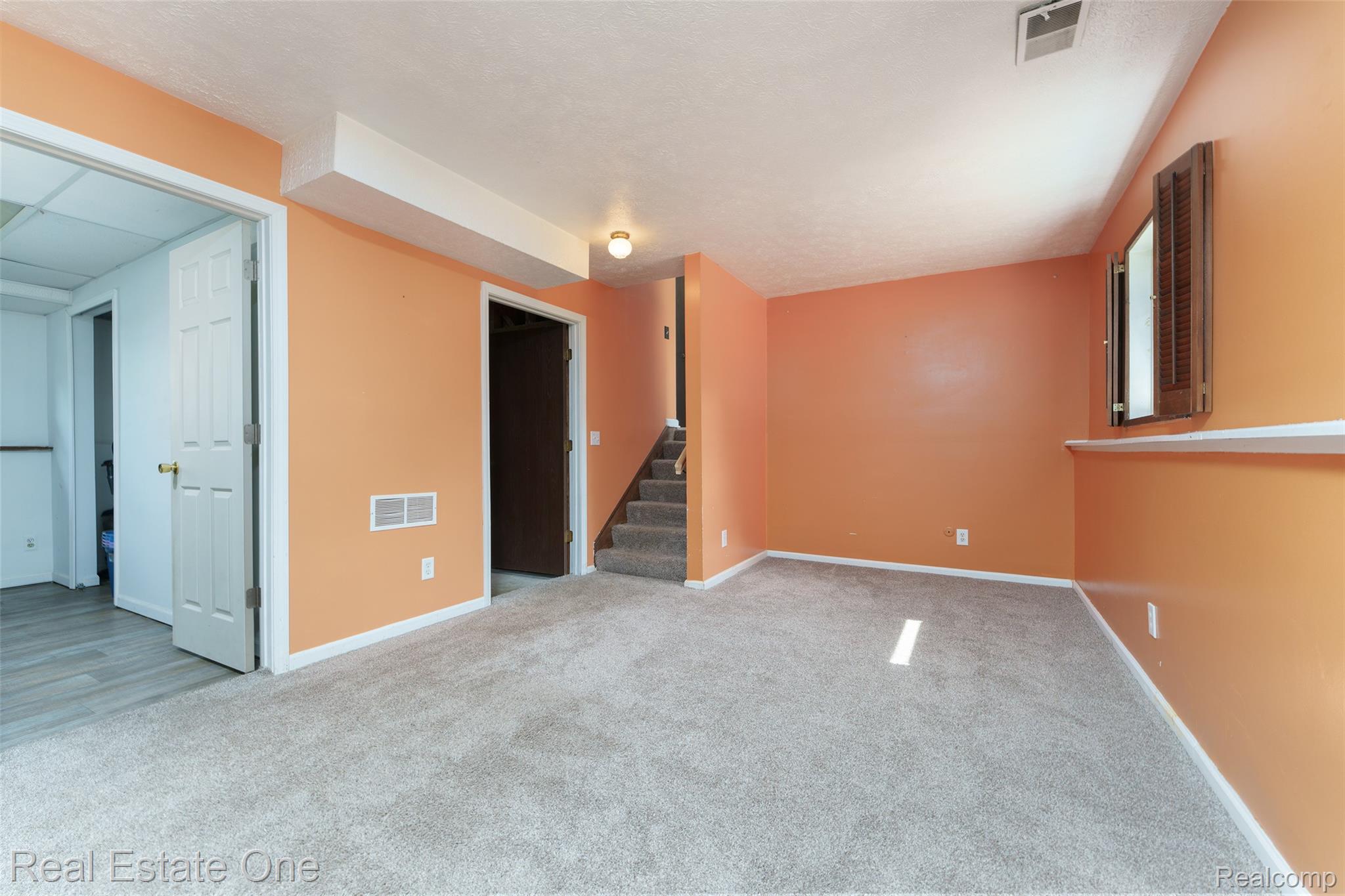 5130 Iosco Road Webberville, MI 48892 - Photo 27 of 39 Carpeted flooring, egress window with wood shutters, and access to a staircase