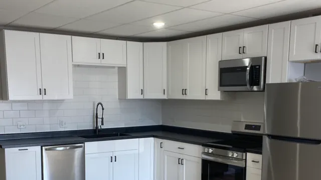 a kitchen with granite countertop white cabinets and black appliances