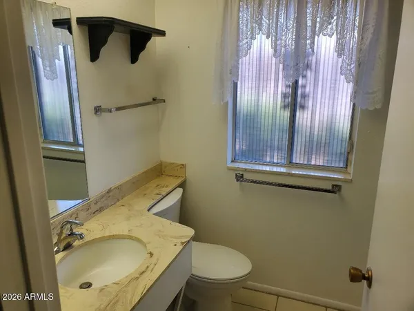 a bathroom with a granite countertop sink toilet and mirror