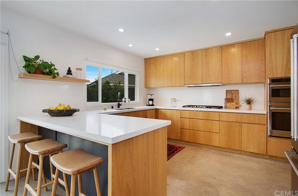 2940 Java Road Costa Mesa, CA 92626 - Photo 9 of 28 a kitchen with stainless steel appliances kitchen island a table chairs sink and cabinets