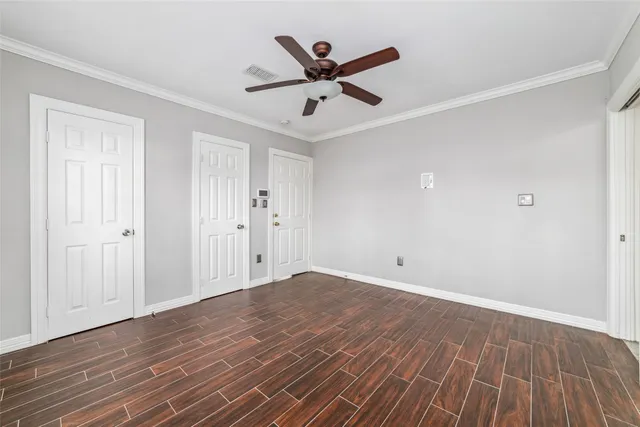 an empty room with wooden floor and ceiling fan