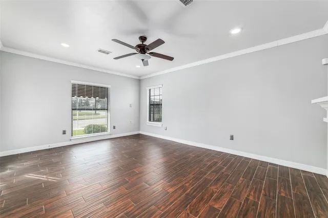 a view of empty room with wooden floor and fan