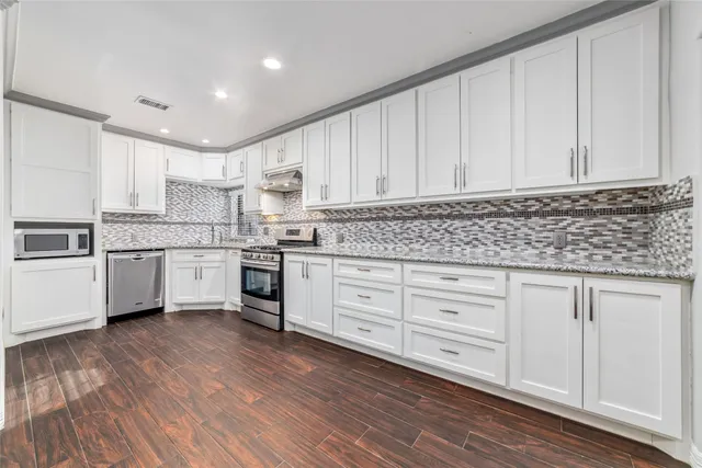 a kitchen with granite countertop white cabinets and white appliances