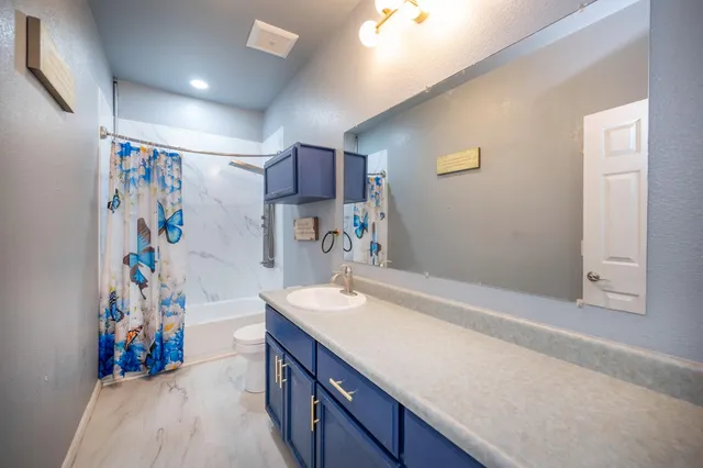 a bathroom with a granite countertop sink mirror vanity and toilet