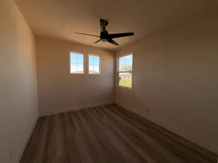 an empty room with windows and fan