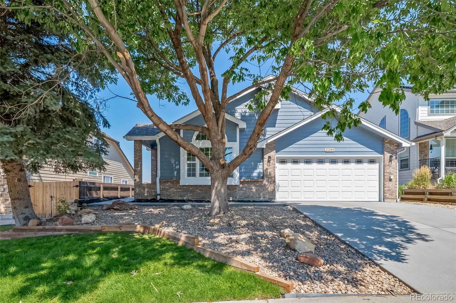 a front view of a house with a tree and a garden