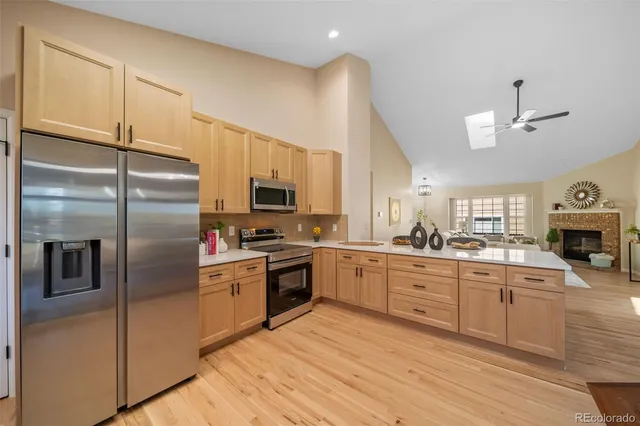 a kitchen with stainless steel appliances granite countertop a refrigerator a stove a sink a dining table and chairs with wooden floor