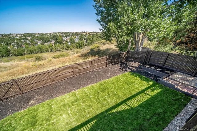 a view of a backyard with a garden and wooden fence