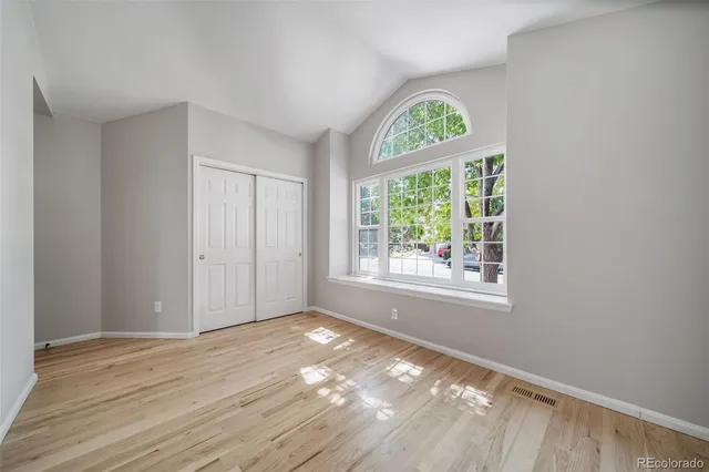 a view of an empty room with wooden floor a painting and a window