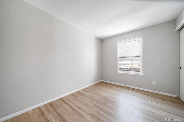 an empty room with wooden floor and window