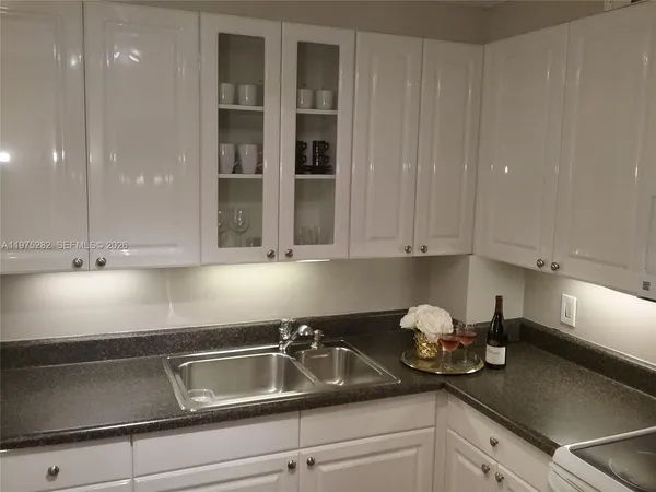 a kitchen with granite countertop white cabinets and white appliances