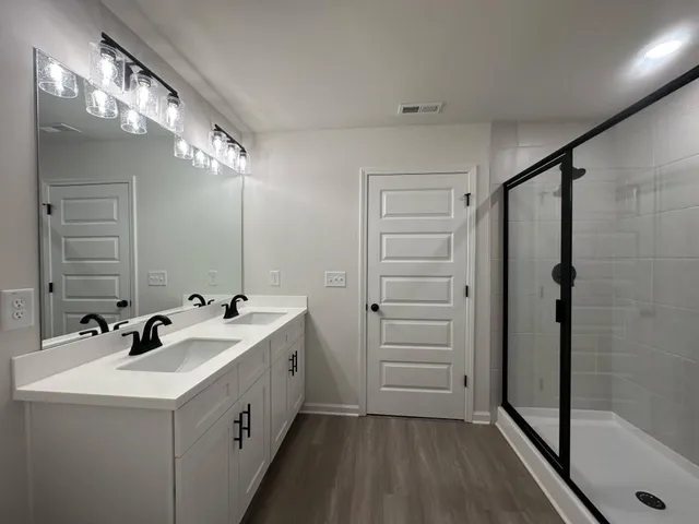 a bathroom with a double vanity sink mirror and shower