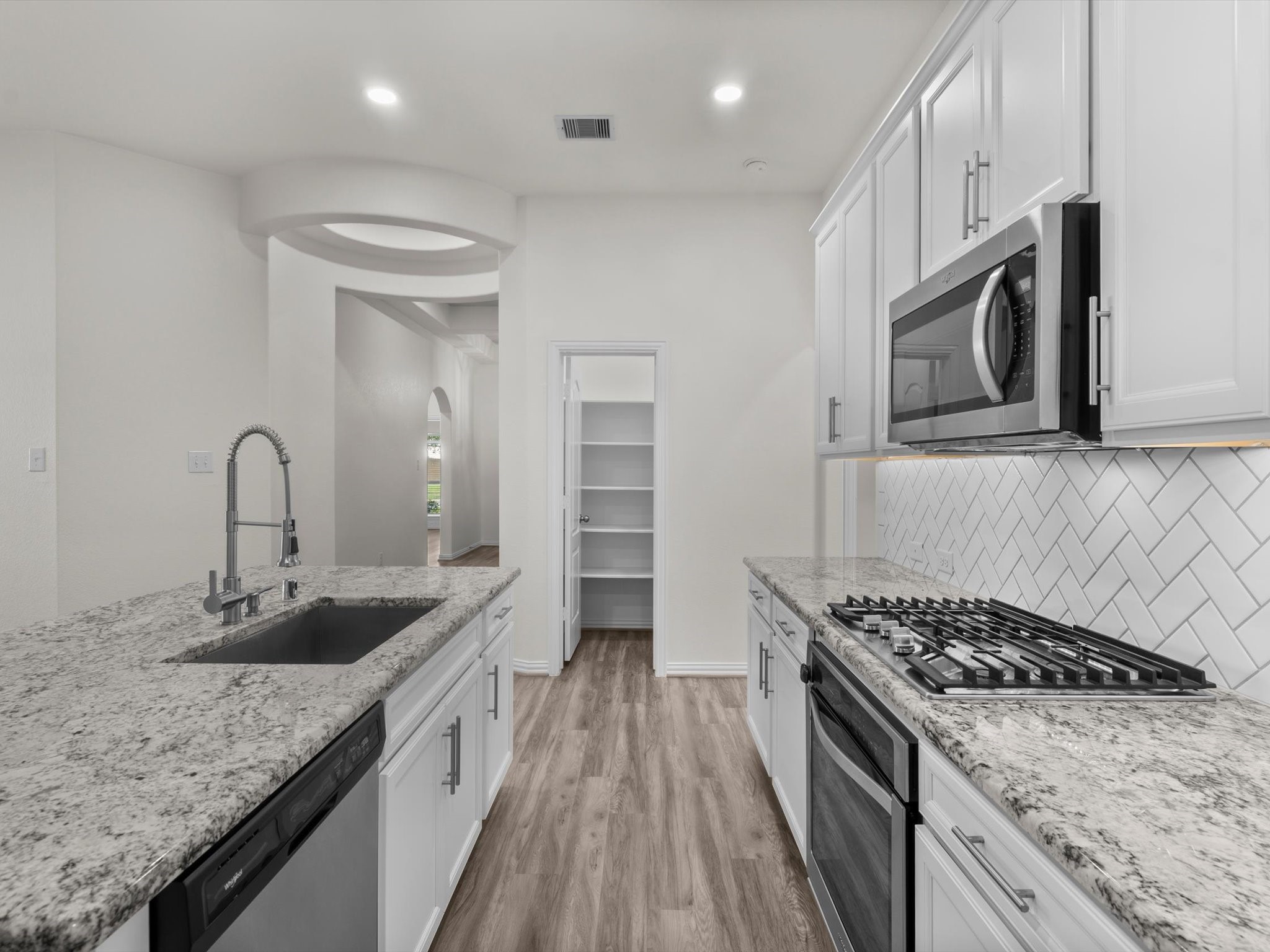 4746 Misty Ranch Drive Spring, TX 77386 - Photo 16 of 49 The kitchen features a herringbone tile backsplash, granite countertops, stainless steel appliances, a gas range, and a spacious island with room for bar seating. Walk In Pantry.