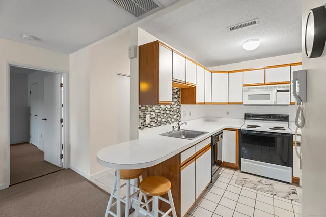 a kitchen with stainless steel appliances granite countertop a sink a stove a refrigerator cabinets and dining table