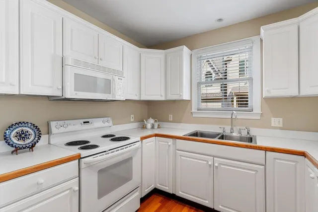 a kitchen with stainless steel appliances granite countertop white cabinets sink and dishwasher with wooden floor