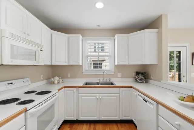 a kitchen with granite countertop white cabinets and white appliances