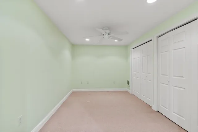 an empty room with a ceiling fan and carpet