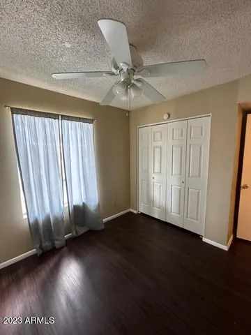 an empty room with wooden floor staircase and windows