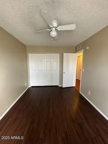 an empty room with wooden floor fan and windows