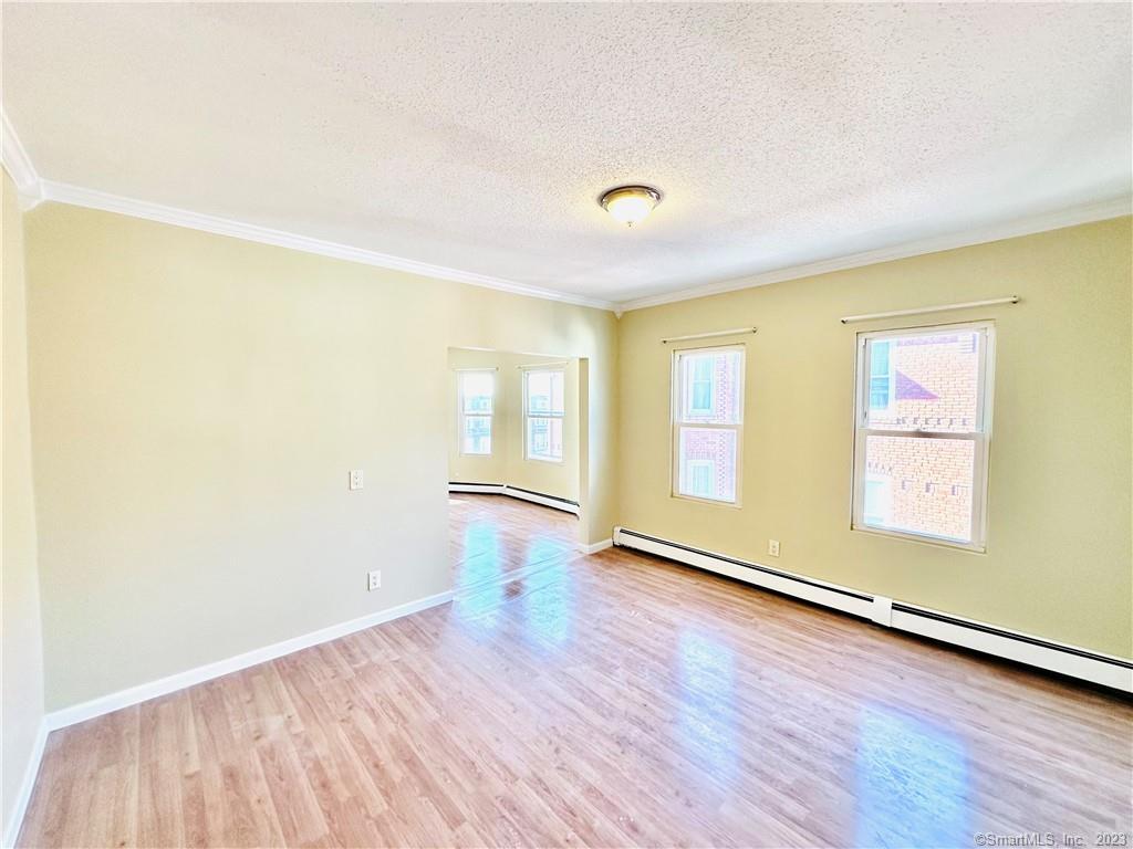 398 Park Street, Unit 3 New Britain, CT 06051 - Photo 4 of 17 an empty room with wooden floor and windows