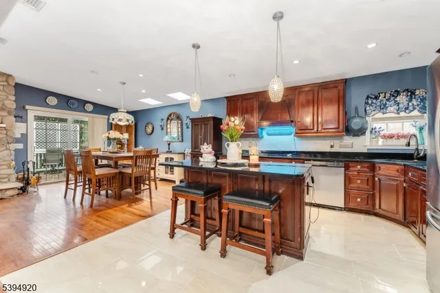 a kitchen with stainless steel appliances granite countertop a stove top oven a sink a dining table and chairs with wooden floor