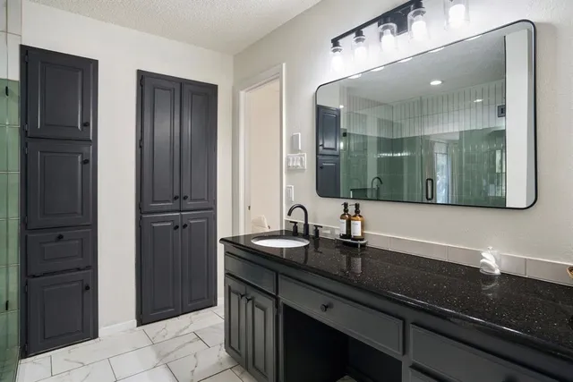 a bathroom with a granite countertop sink a large mirror and a shower