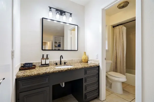 a bathroom with a granite countertop toilet a sink and a mirror