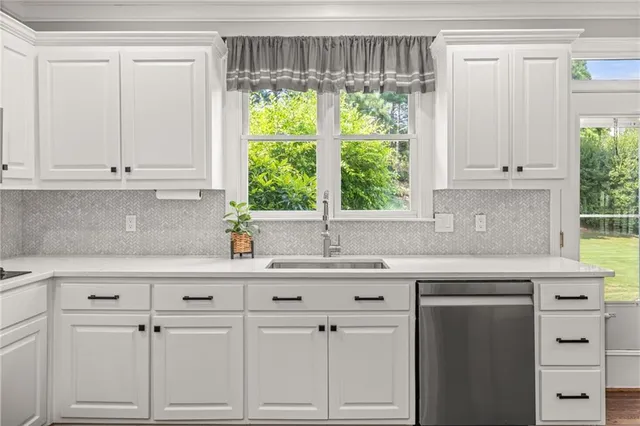 a kitchen with granite countertop white cabinets and a window
