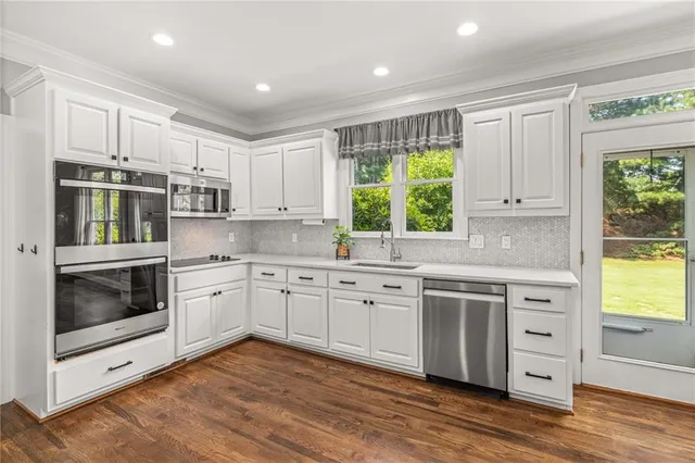 a kitchen with stainless steel appliances granite countertop a stove a sink and a microwave