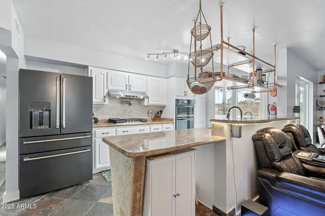 a kitchen with stainless steel appliances granite countertop a sink a stove and a refrigerator