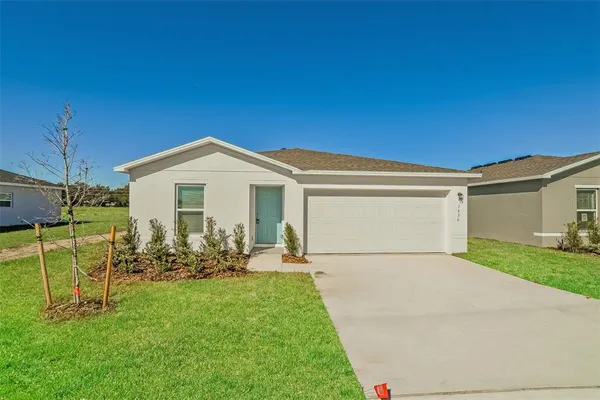 a view of a white house with a big yard and potted plants