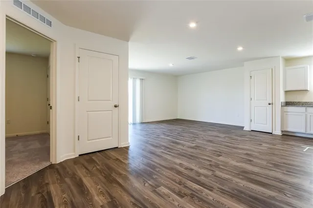 an empty room with wooden floor & cabinet and windows