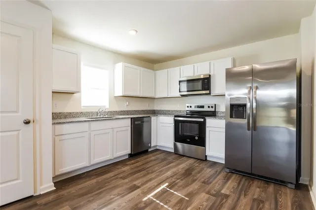 a kitchen with granite countertop a refrigerator and a stove top oven