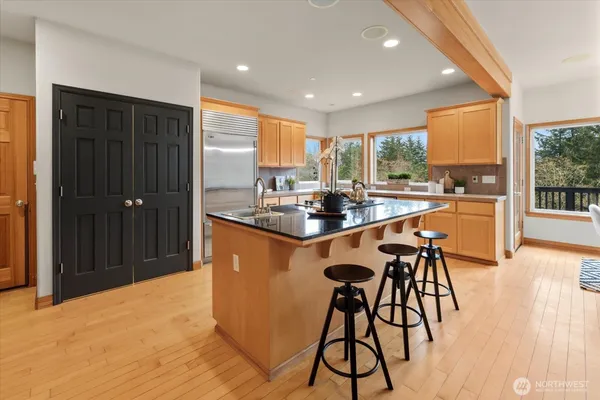 a dining hall with stainless steel appliances granite countertop a stove a sink a refrigerator and a dining table with garden view