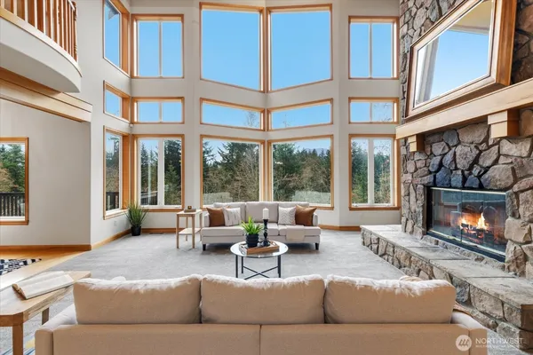a living room with furniture a fireplace and floor to ceiling windows