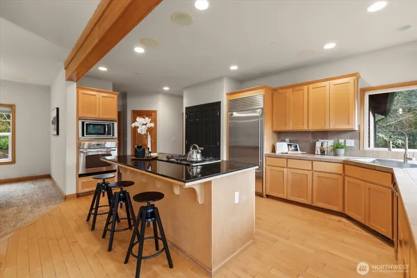 a kitchen with stainless steel appliances kitchen island granite countertop a stove a sink and a refrigerator with wooden floor