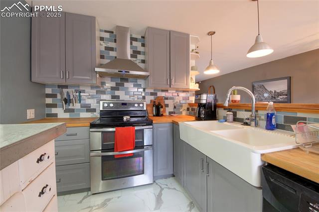 Kitchen with black dishwasher, marble finish floor, double oven range, gray cabinetry, and wall chimney range hood