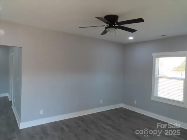 an empty room with a ceiling fan and window