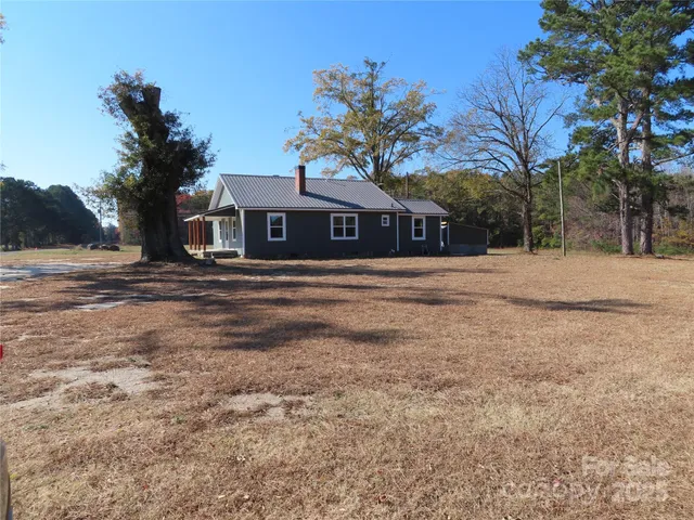 a front view of a house with a yard covered with trees