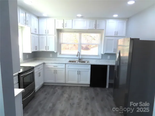 a kitchen with granite countertop a sink stainless steel appliances and window