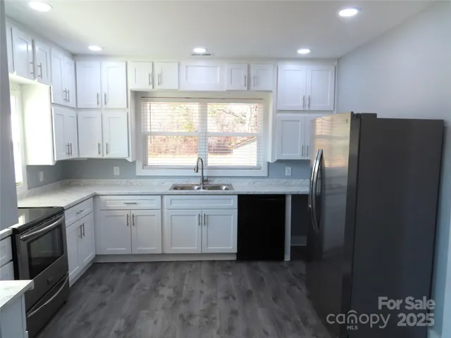 a kitchen with stainless steel appliances granite countertop a refrigerator a sink a stove a microwave and wooden cabinets