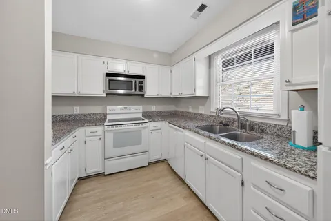 a kitchen with granite countertop white cabinets and a sink
